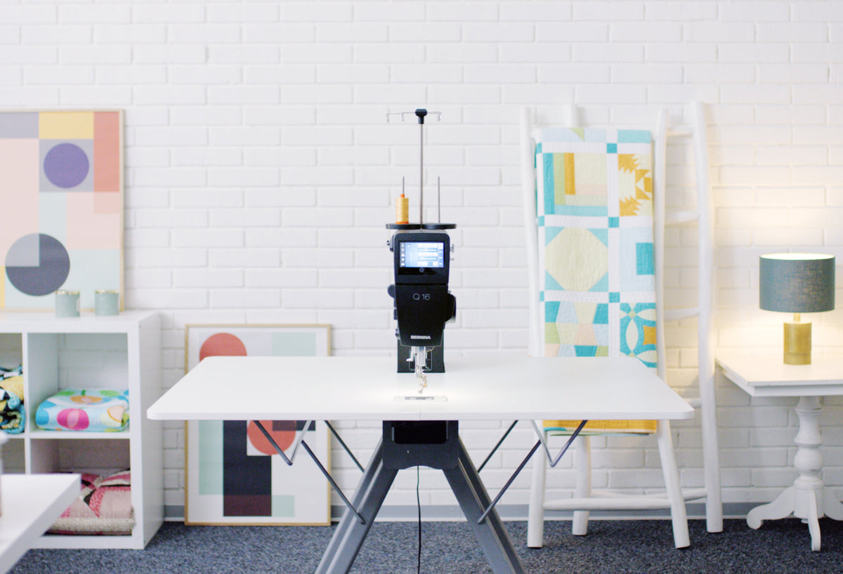Representative BERNINA Q-Series sit-down quilting table setup viewed from the front; machine and accessories may differ from selected Q16 PLUS package