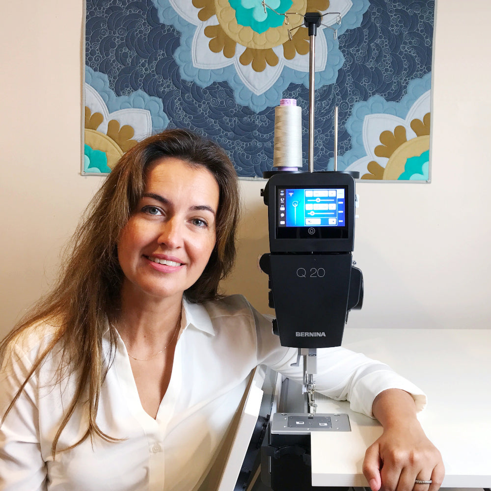BERNINA Q20 sit-down longarm front view with Carolina Asmussen, showing the touchscreen and needle area; illustrative studio setting
